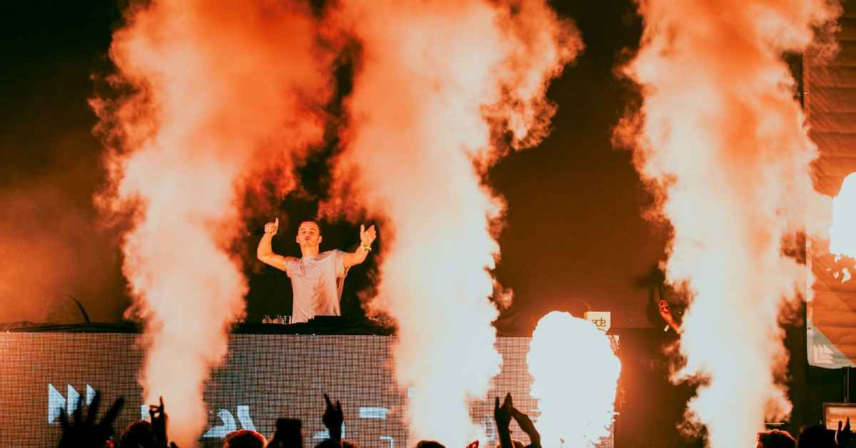 A DJ is on stage and smoke everywhere in background